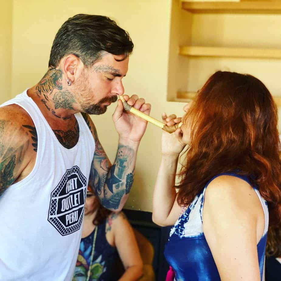 Dos personas aplicándose tabaco rapé con un accesorio tepi